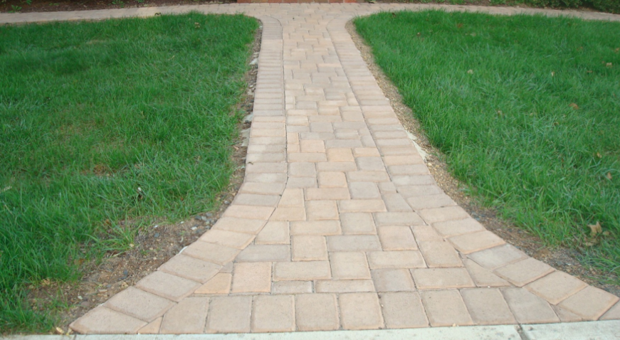 Brick pathway curving through green grass.