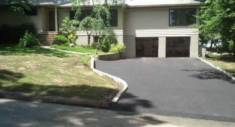 House with driveway, two-car garage, and a sloped front yard with curb.