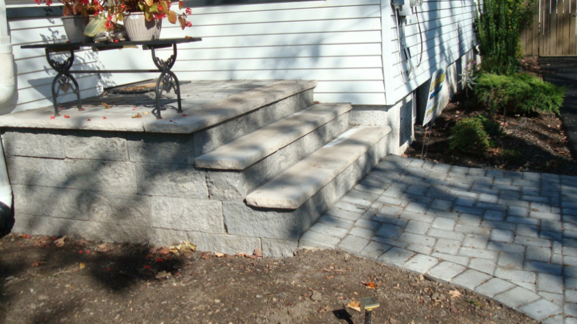 Stone steps and walkway leading to a house with a small table and flower arrangement on the porch.