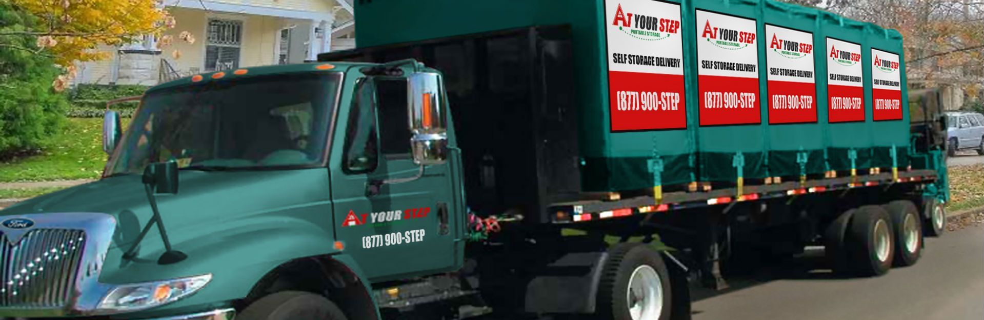 Green garbage truck hauling green waste bins on a street, side view