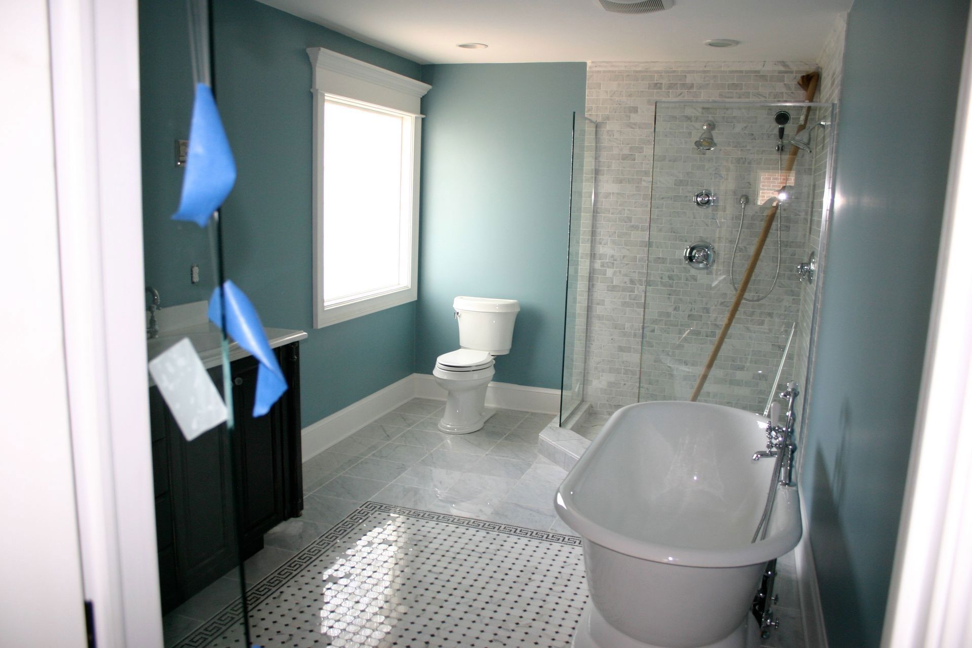Accessible bathroom with walk-in shower, toilet, and freestanding tub in light blue and white.