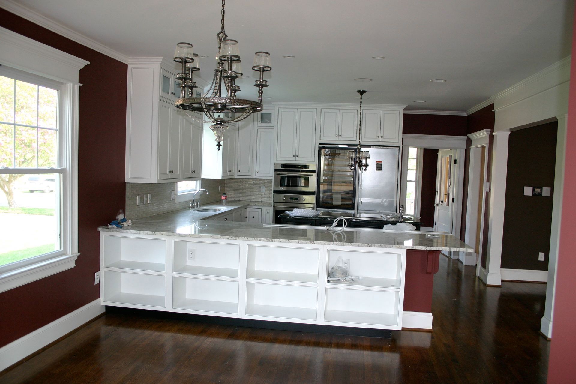 Bright kitchen with white cabinets, dark wood floors, marble island, and a chandelier