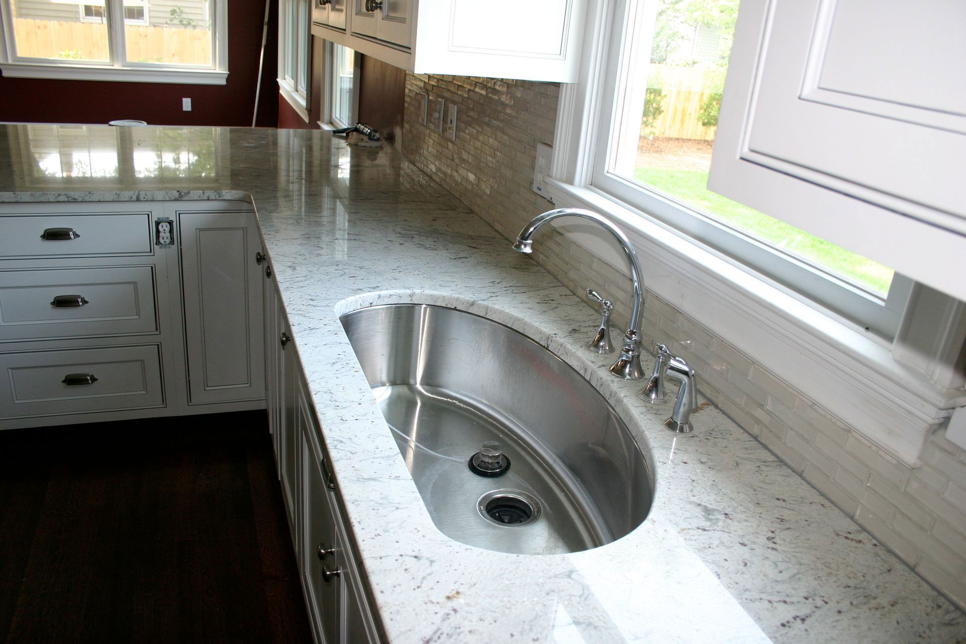 Modern kitchen with white cabinets, granite countertop, stainless sink, and window above the sink