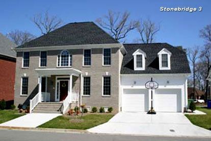 Two-story gray brick house with a dark roof and a two-car garage. A basketball hoop is in front.