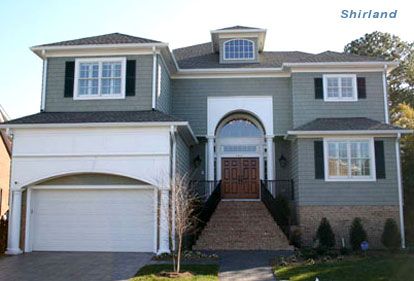 Two-story house with green siding, white trim, and a brick pathway leading to the front door.