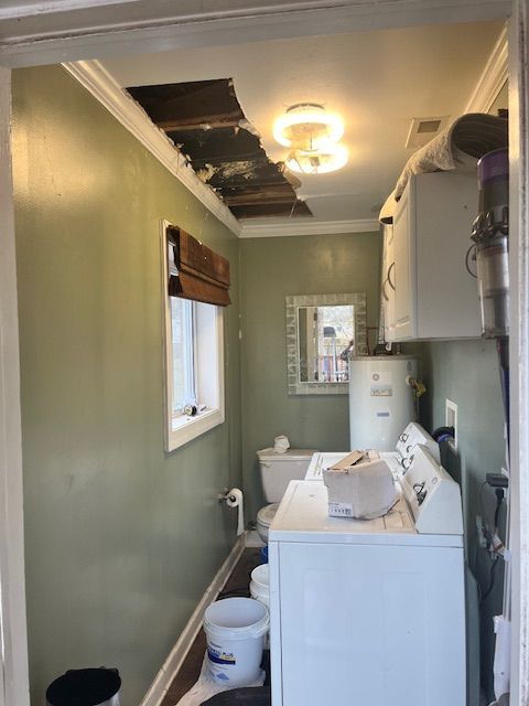 Bathroom with significant ceiling damage, green walls, white appliances, and a small window.