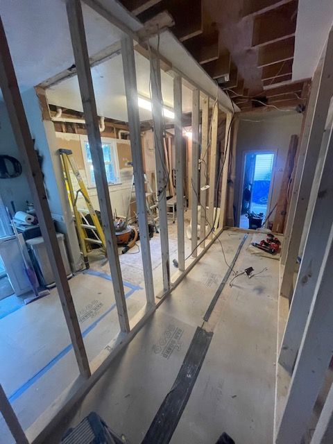 Interior view of a room under construction with exposed wooden wall framing.