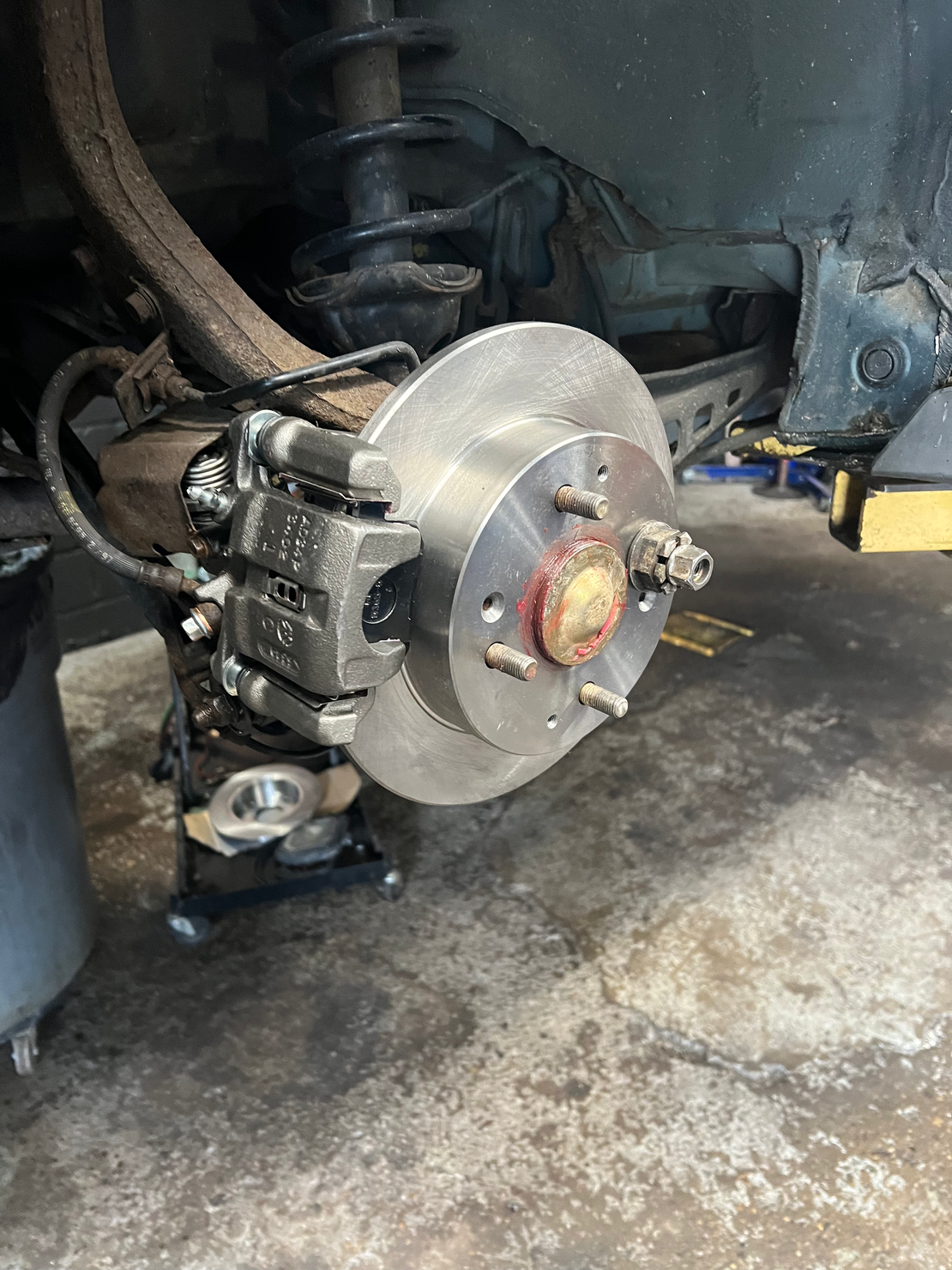 Mechanic removing a car brake rotor with a wrench and gloved hands