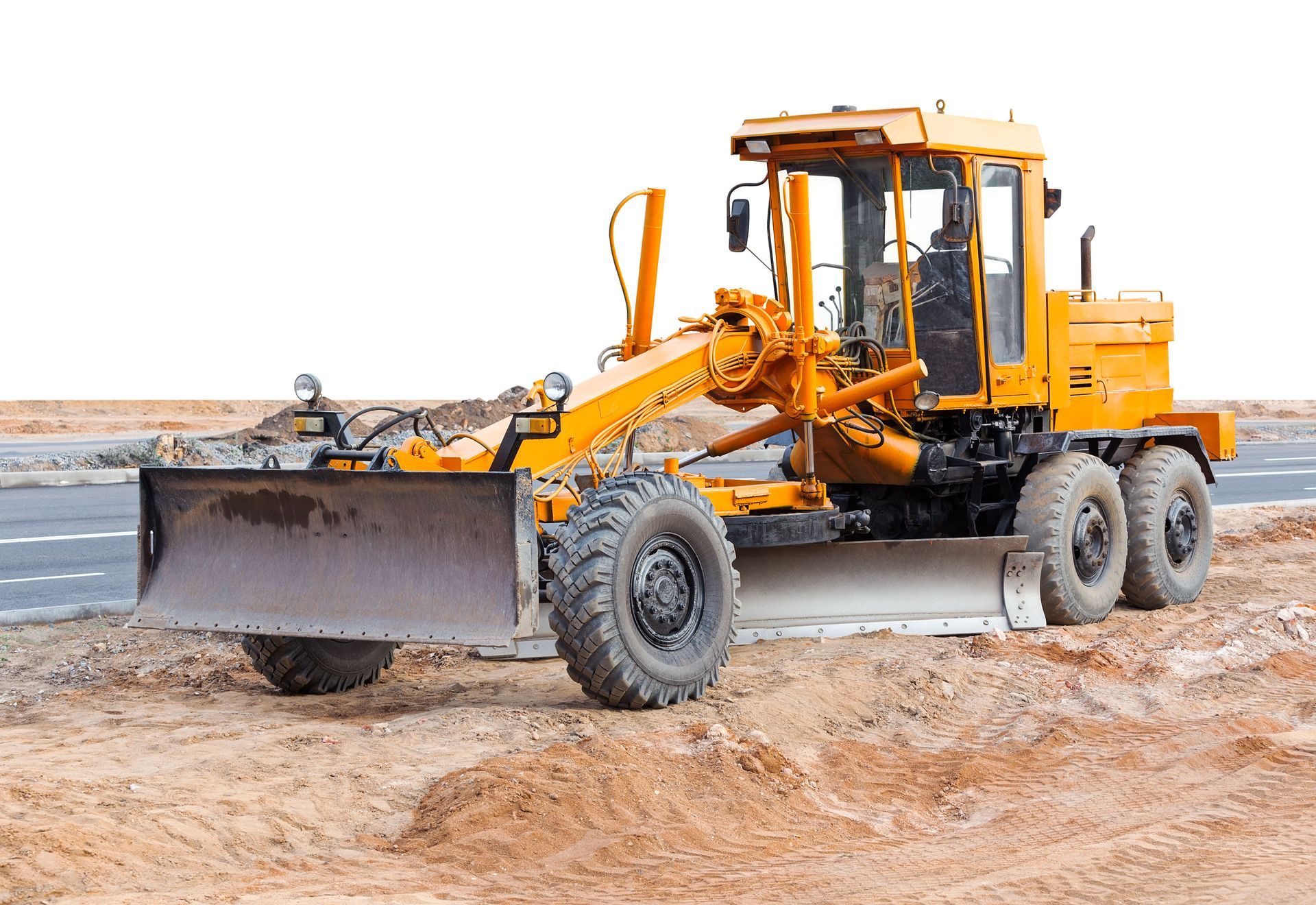 Yellow road grader on dirt, preparing a road surface.