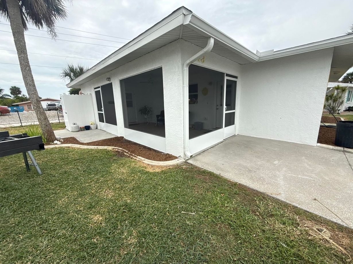White house exterior with a covered porch, concrete driveway, and grassy yard