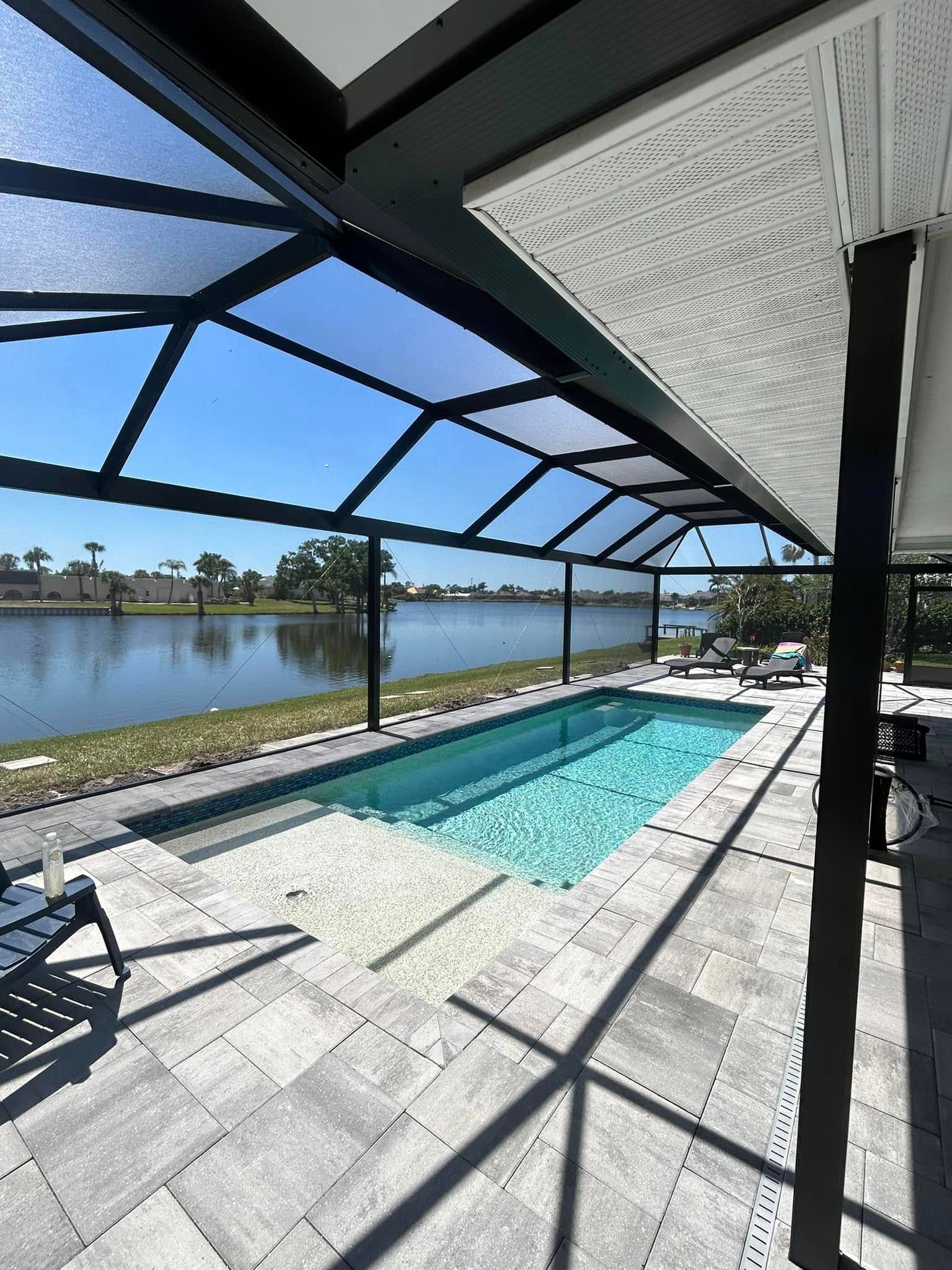 Covered pool with lake view, screened patio, and lounge chairs in bright sunlight