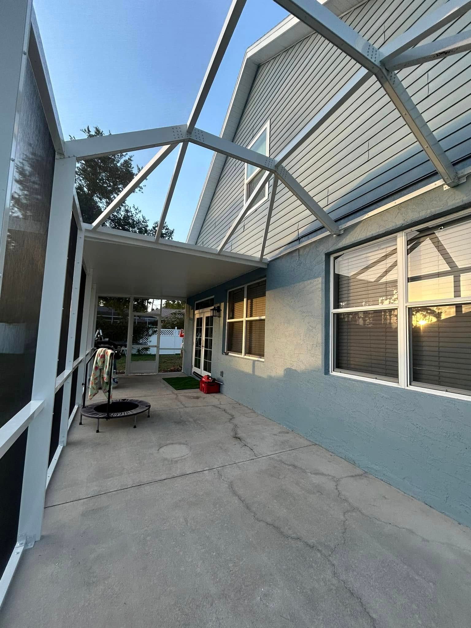 Covered walkway beside a blue building with metal beams, windows, and a concrete path at sunset