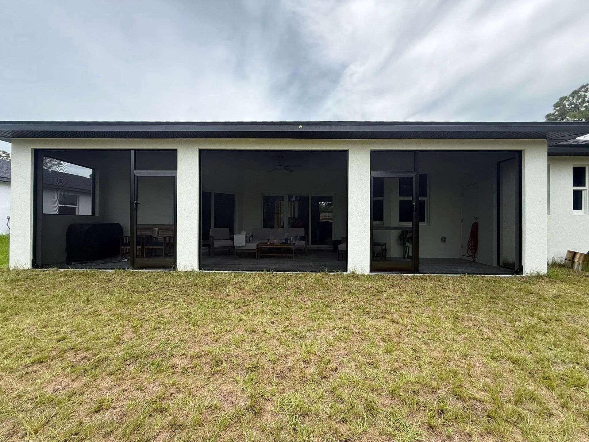 Modern house exterior with a covered patio and large glass doors overlooking a grassy yard