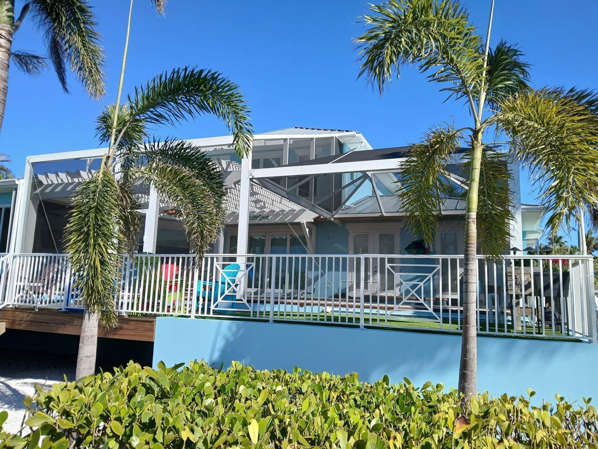 Modern white beach house with palm trees and a blue sky