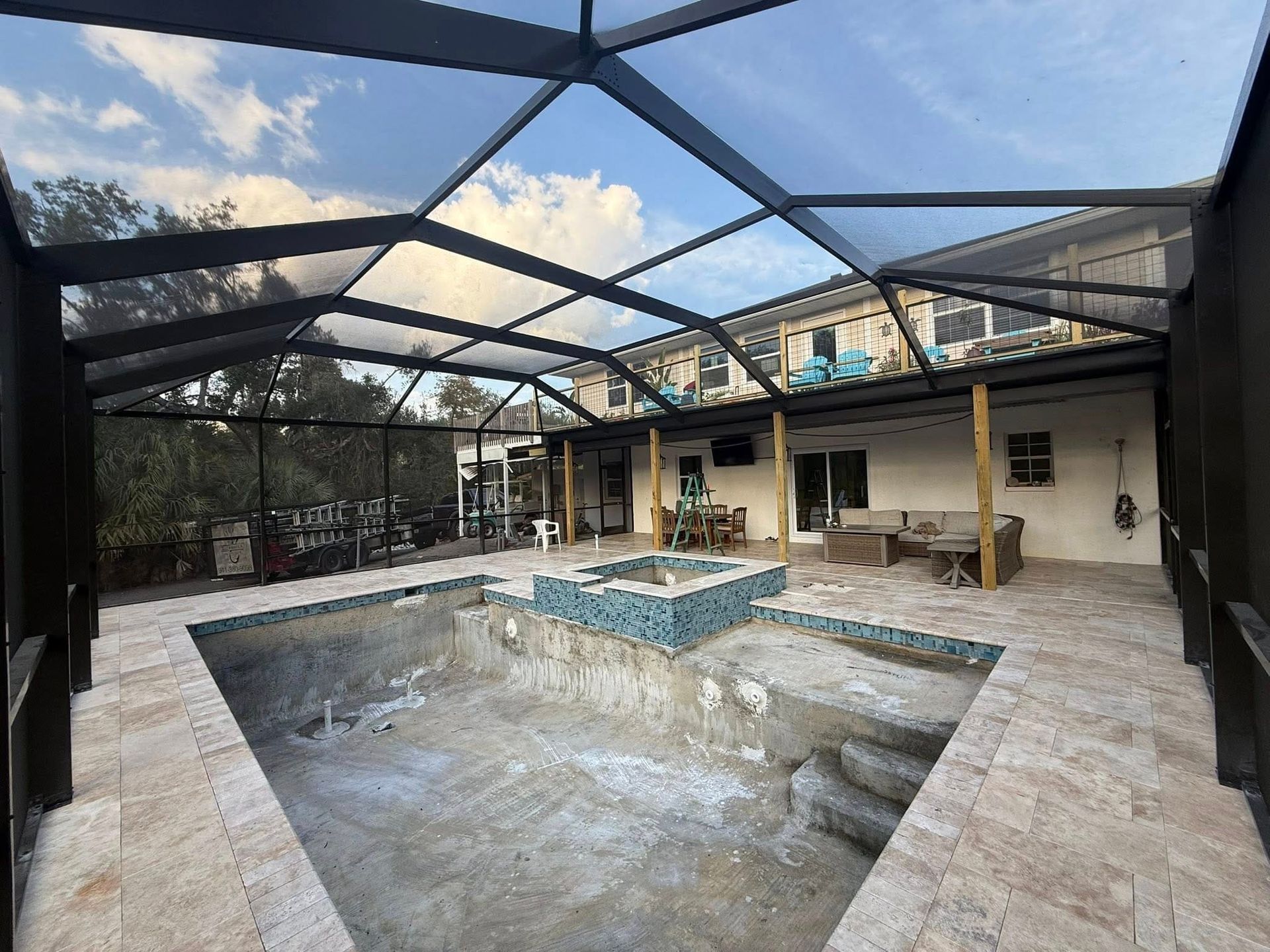 Empty covered patio with a screened enclosure and a small central fountain or pool basin under construction