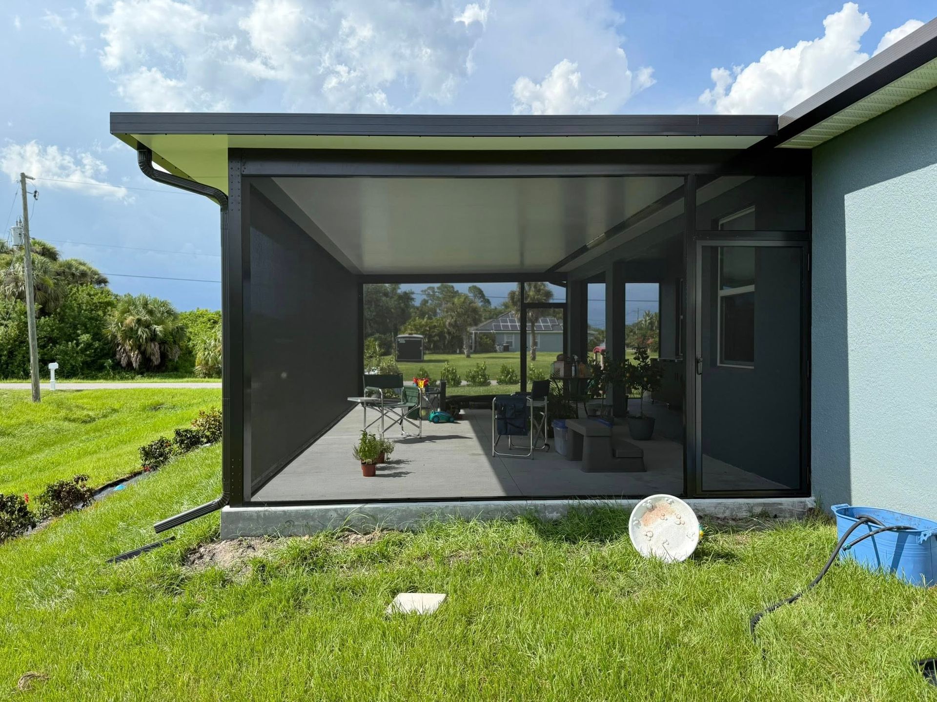 Modern house patio with screened porch, green lawn, and blue sky