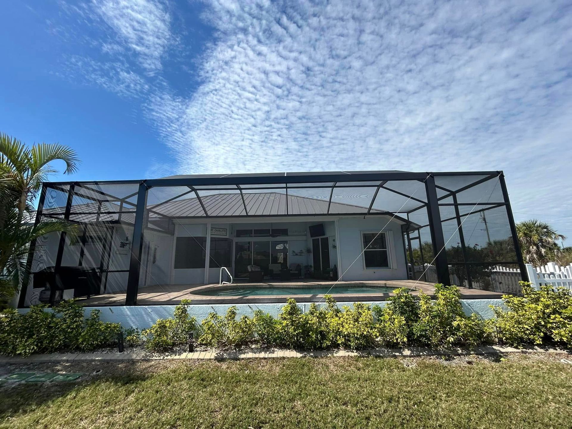 Modern house with a screened-in patio and pool under a bright blue sky