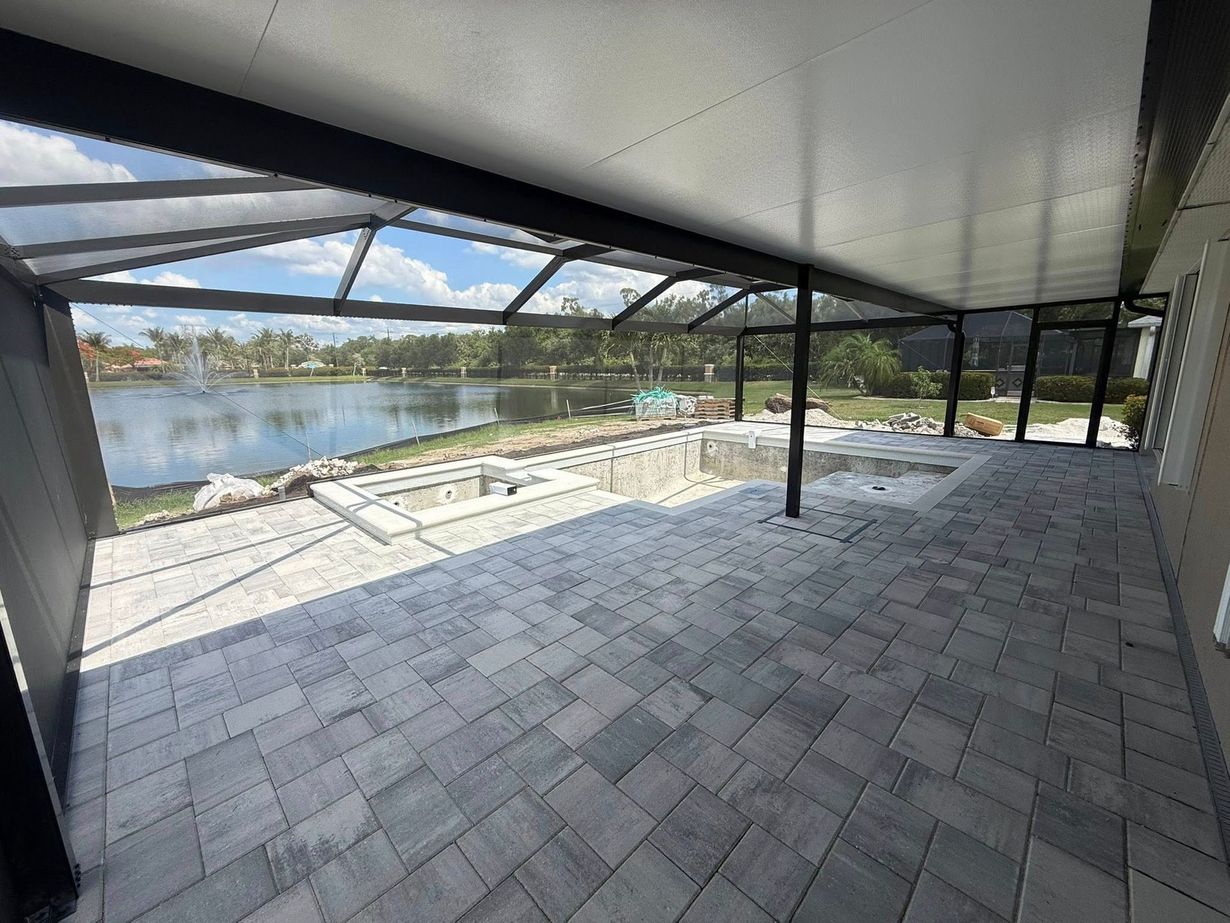 Covered patio with gray pavers overlooking a lake and distant hills