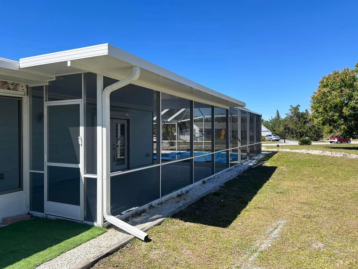 Exterior of a blue building with white trim and a screened porch beside a grassy lawn