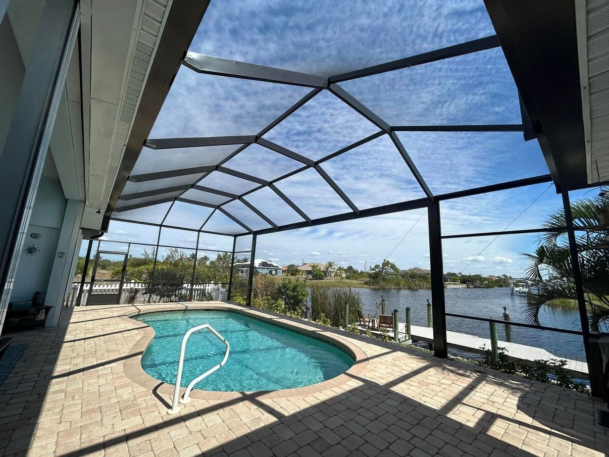 Screened pool patio with blue water, tiled deck, and a lake view beyond the railing