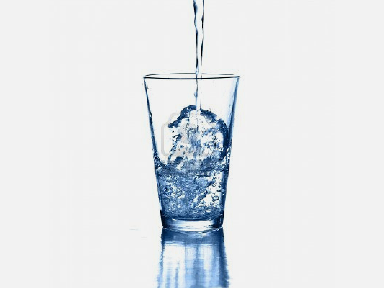 Water pouring into a clear glass, creating splashes on a white background.