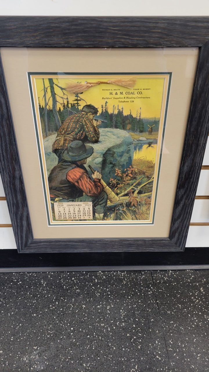 A framed picture of two men fishing in the woods.