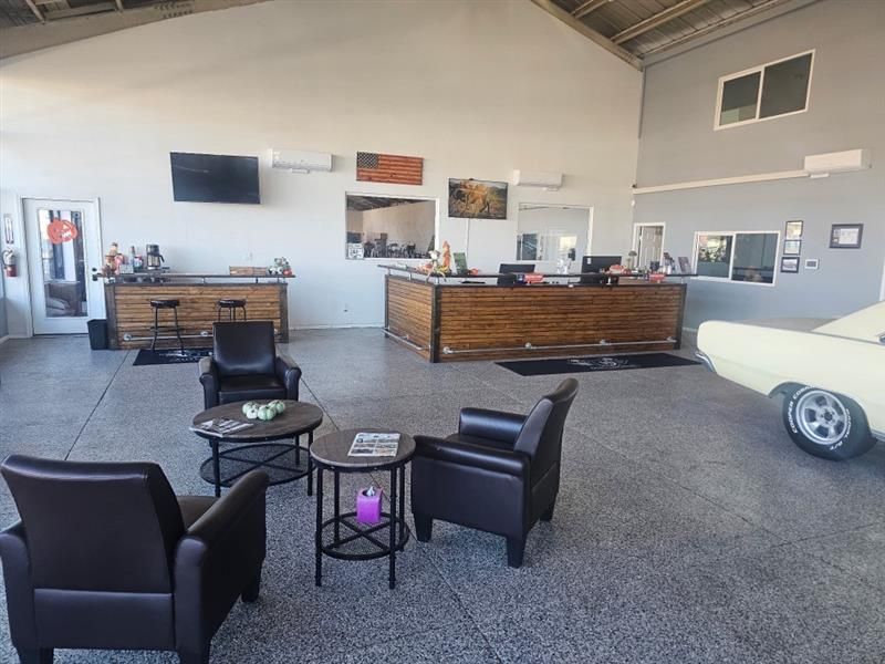 Five people in work uniforms posing in front of a vehicle lift in a garage.