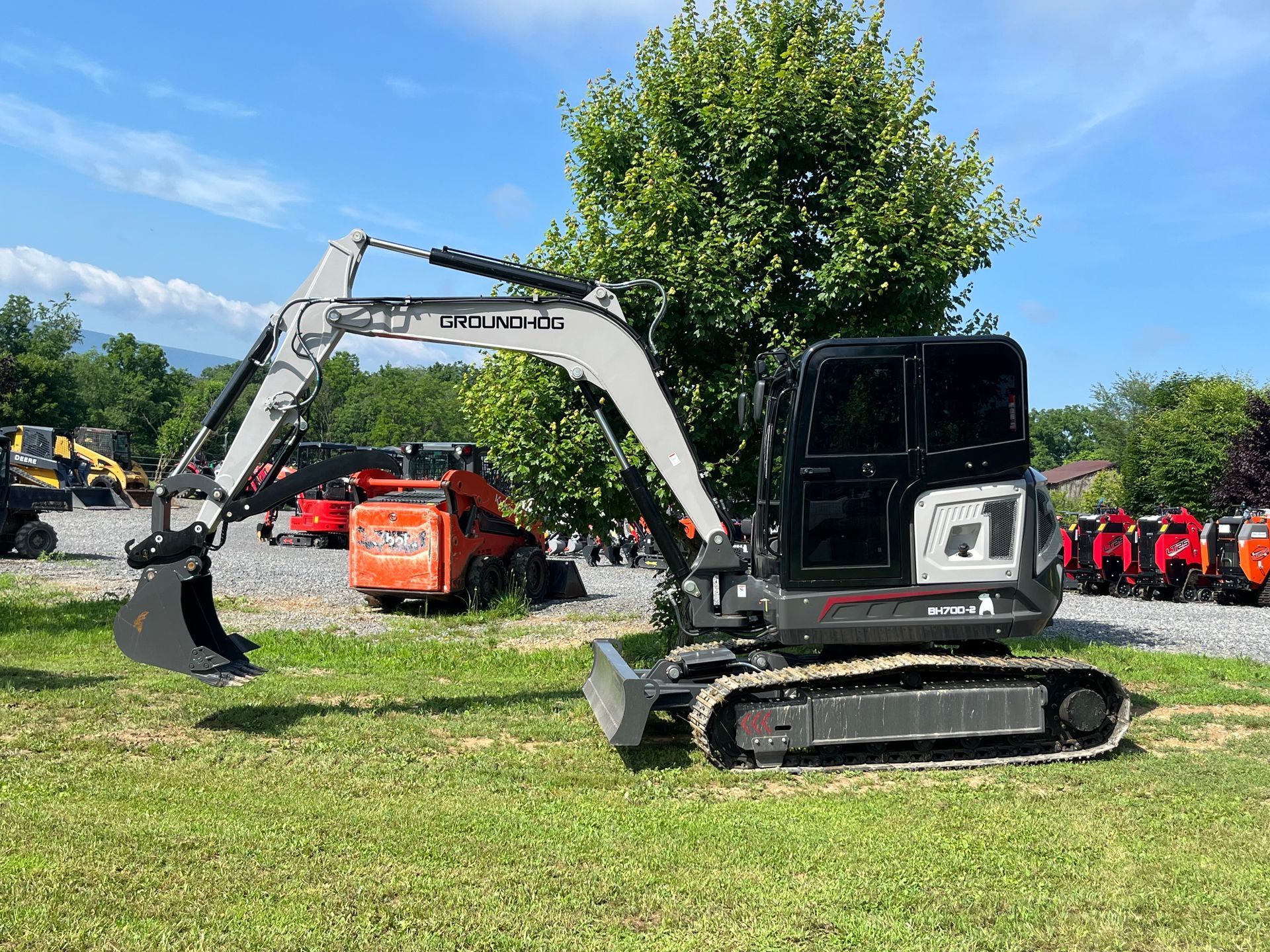 Excavator with bucket parked on grass at an outdoor worksite.