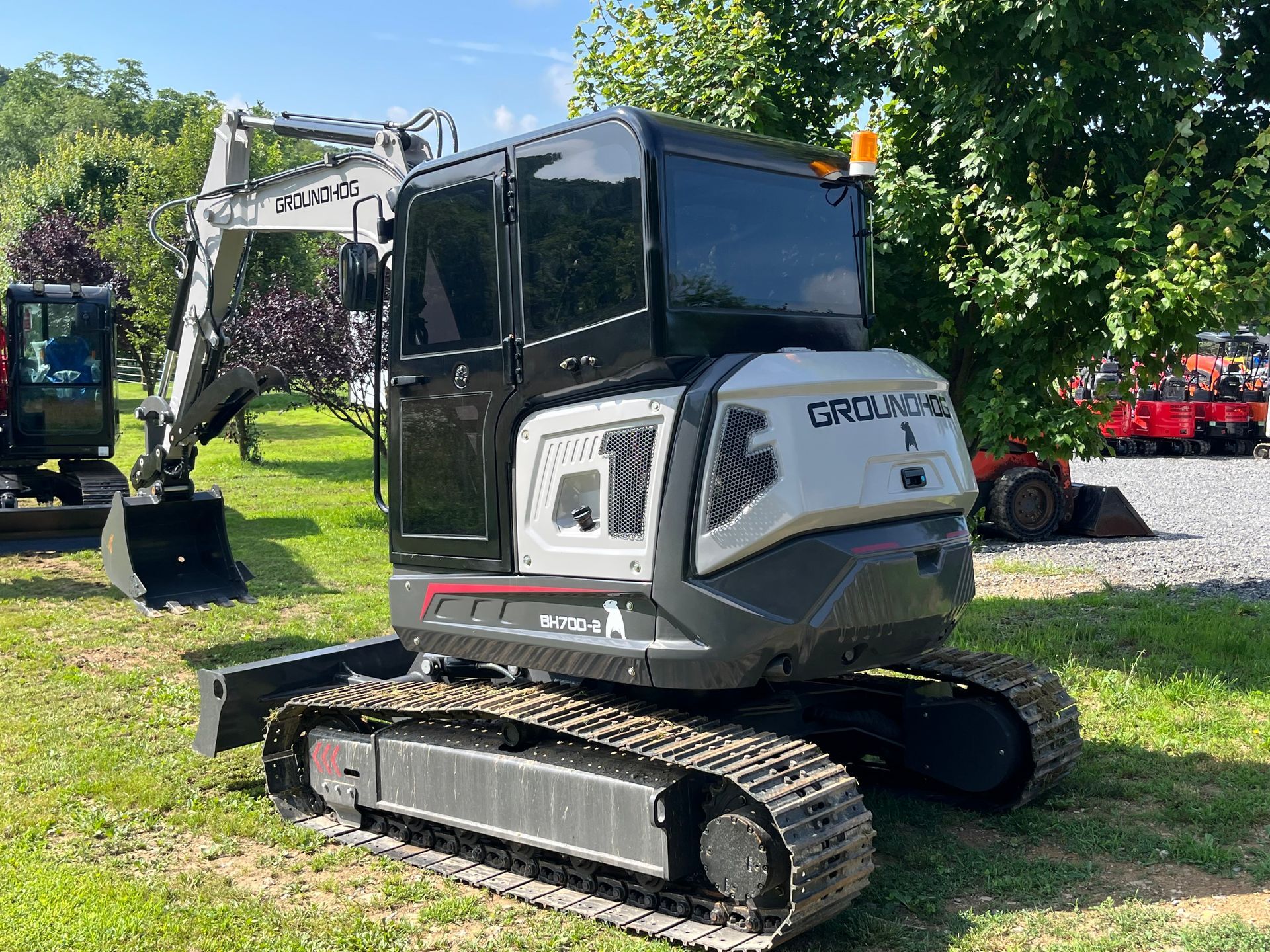 Excavator on tracks parked on grass at an outdoor equipment display.