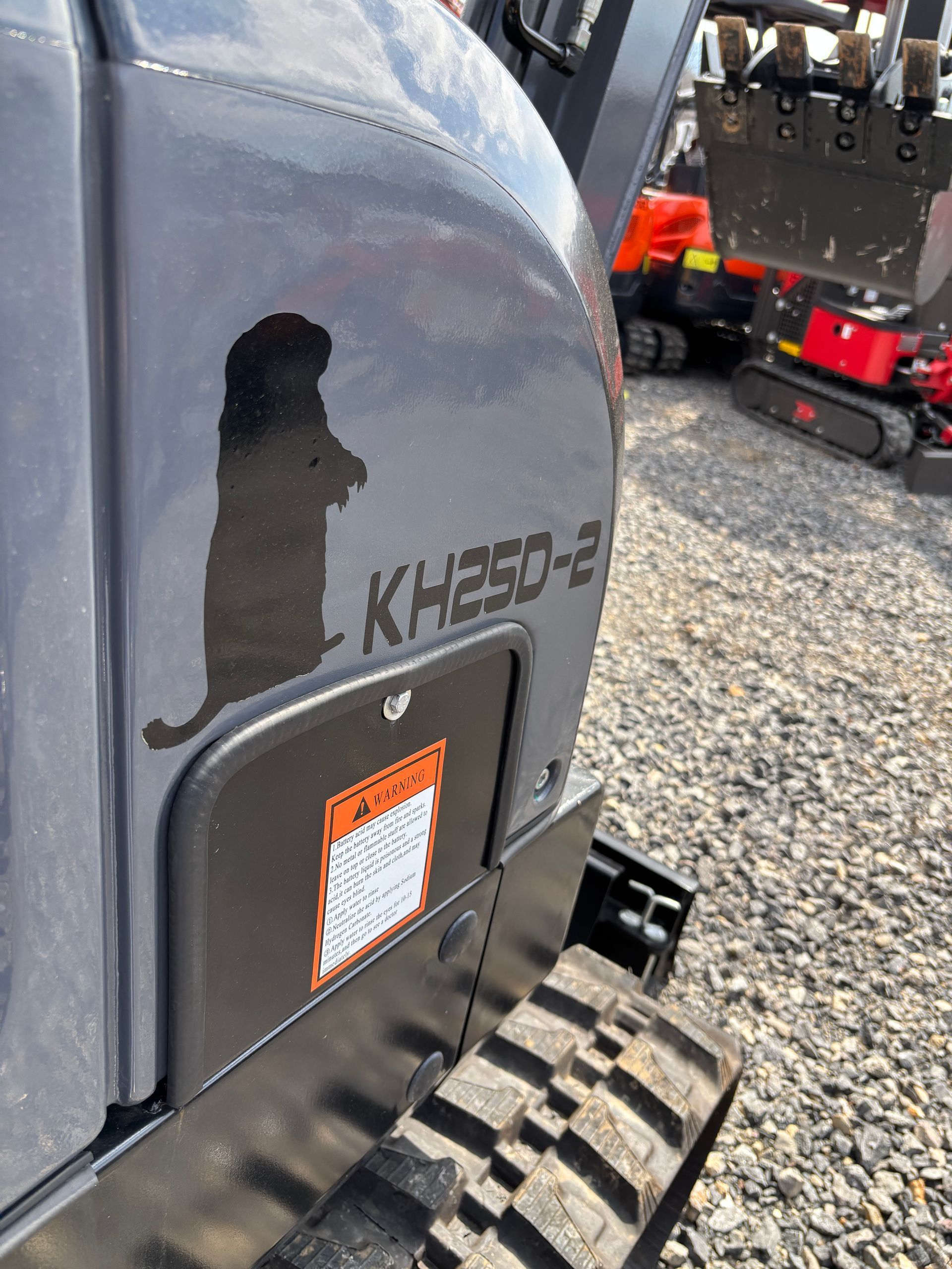 A close-up view of a gray excavator side panel featuring a black beaver silhouette and the model label 