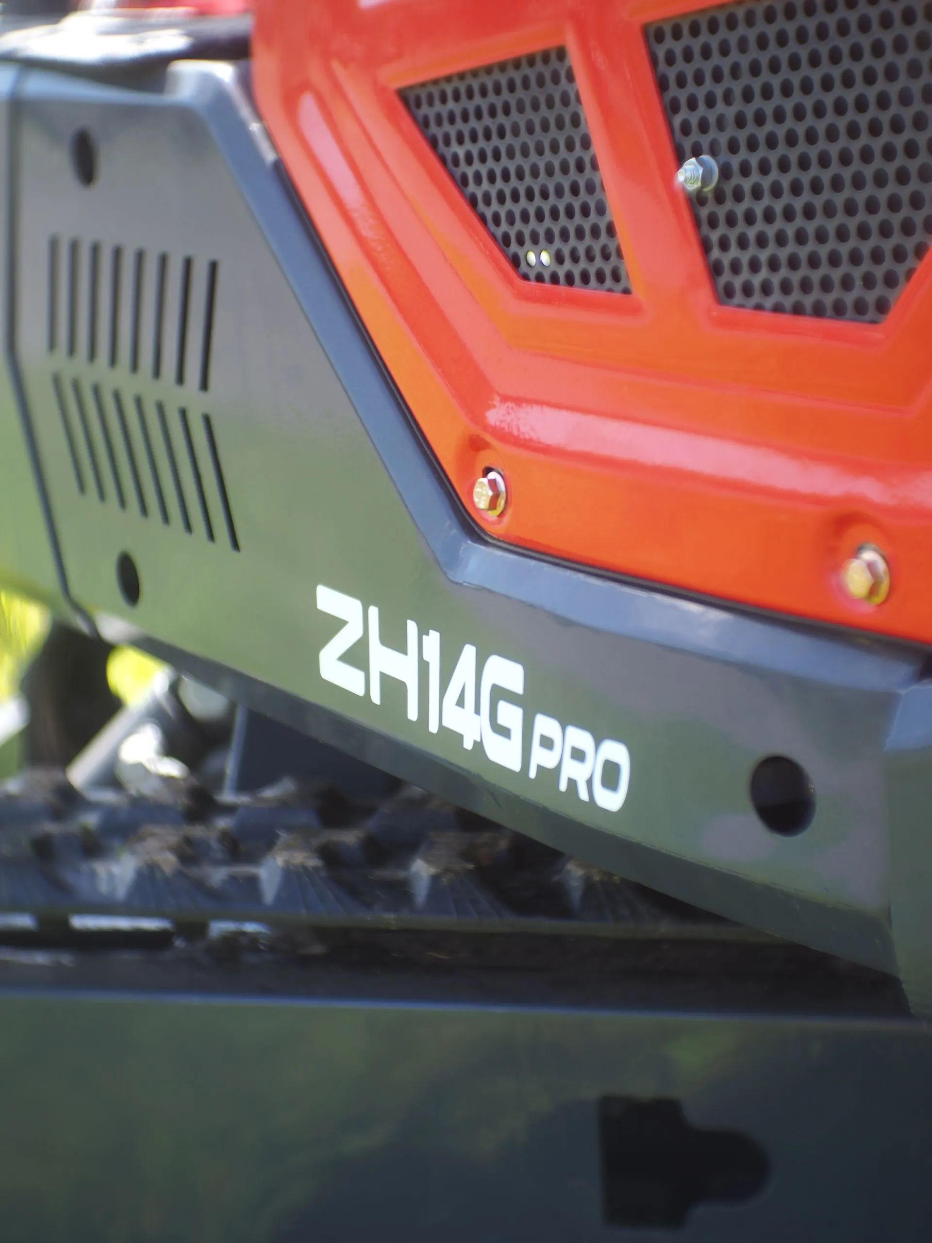 Close-up of a ZH14G PRO excavator, showing its black side panel with white lettering and a vibrant orange engine cover.