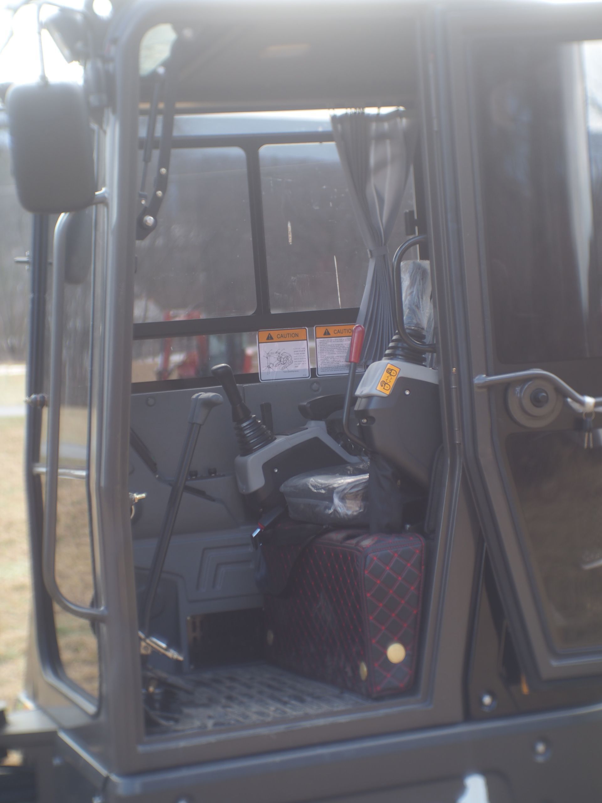 The interior cabin of a heavy construction vehicle featuring a driver's seat, control levers, and a patterned foot mat.