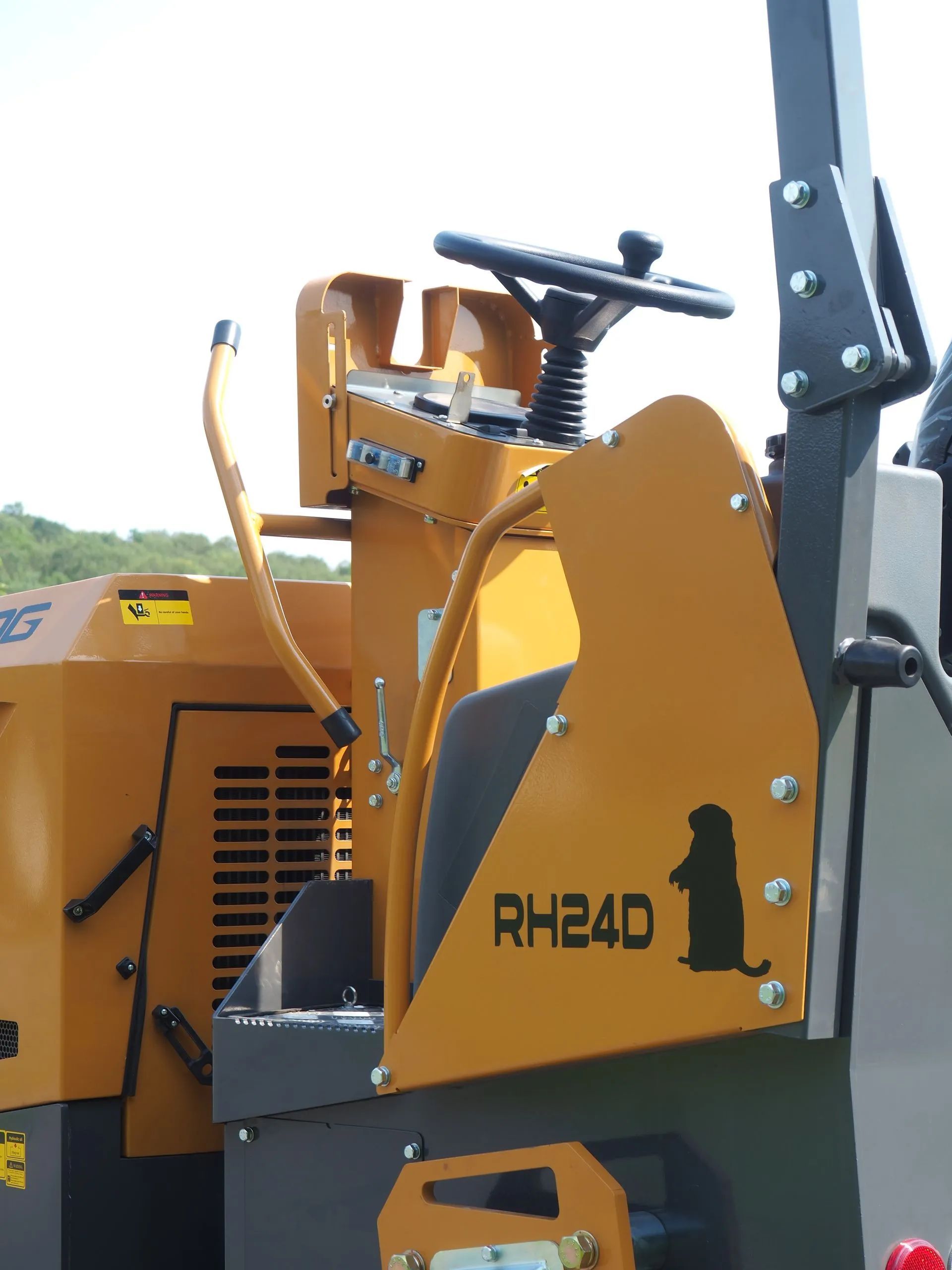 A yellow RH24D construction vehicle featuring a silhouette of a groundhog, showing the operator's console and steering.