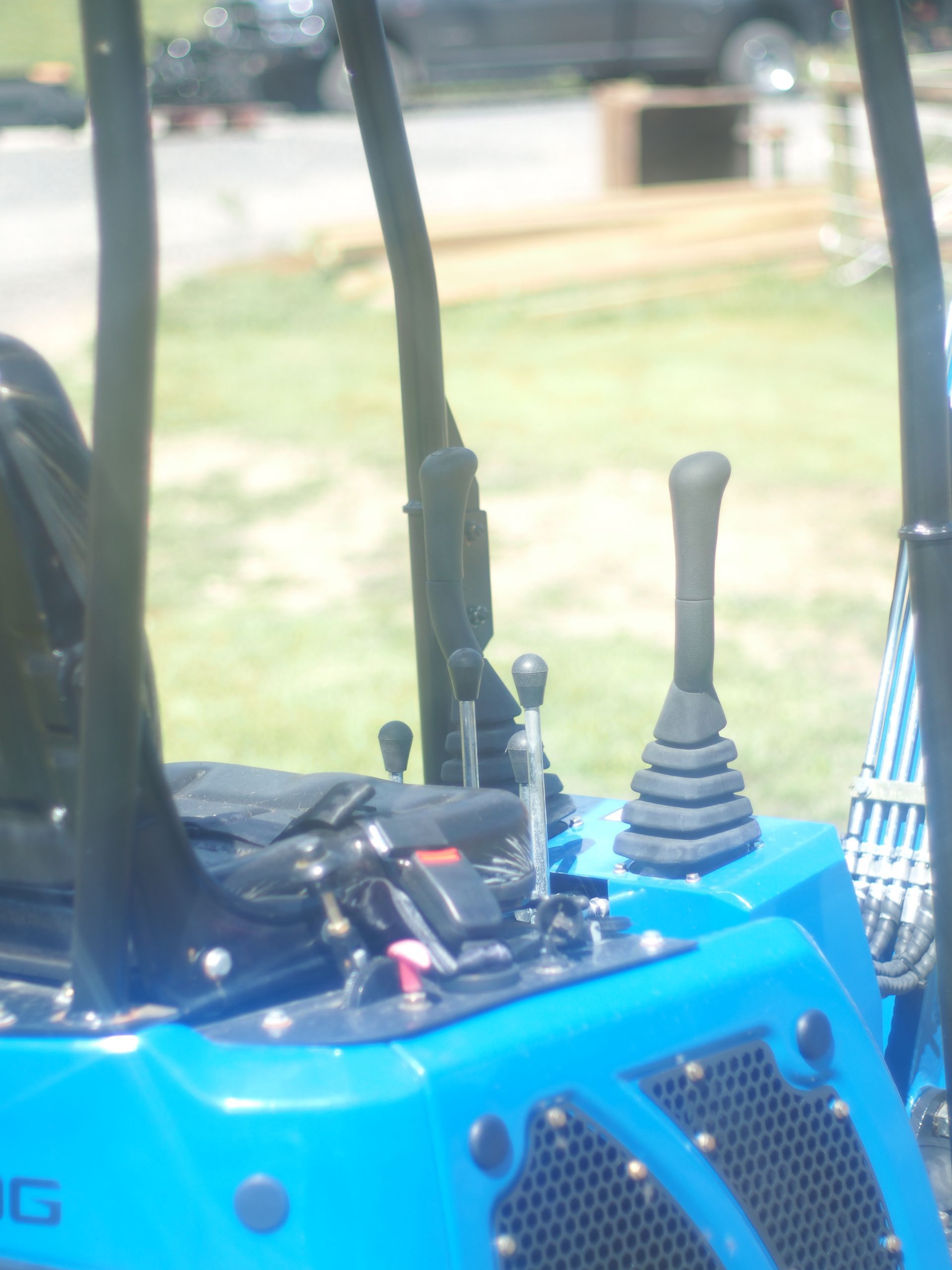 Controls and seat of a blue compact tractor parked in a grassy area.