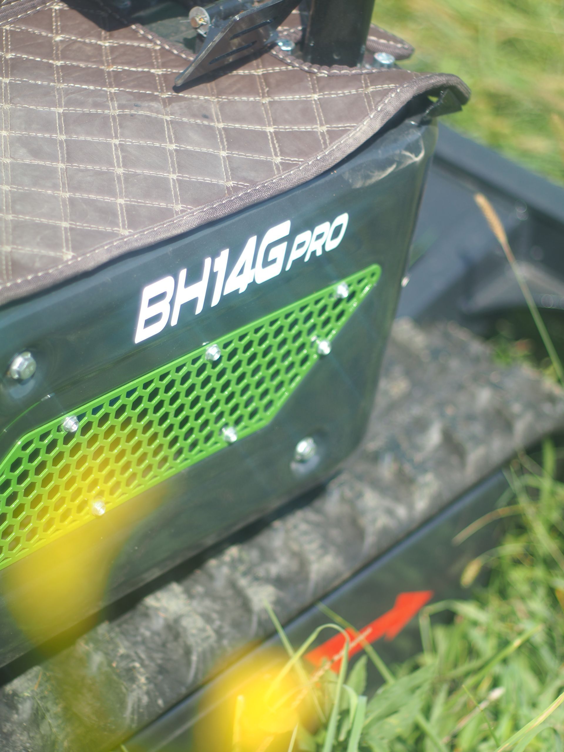 Close-up of a BH14G PRO piece of equipment with a green mesh vent, positioned on a grassy surface.