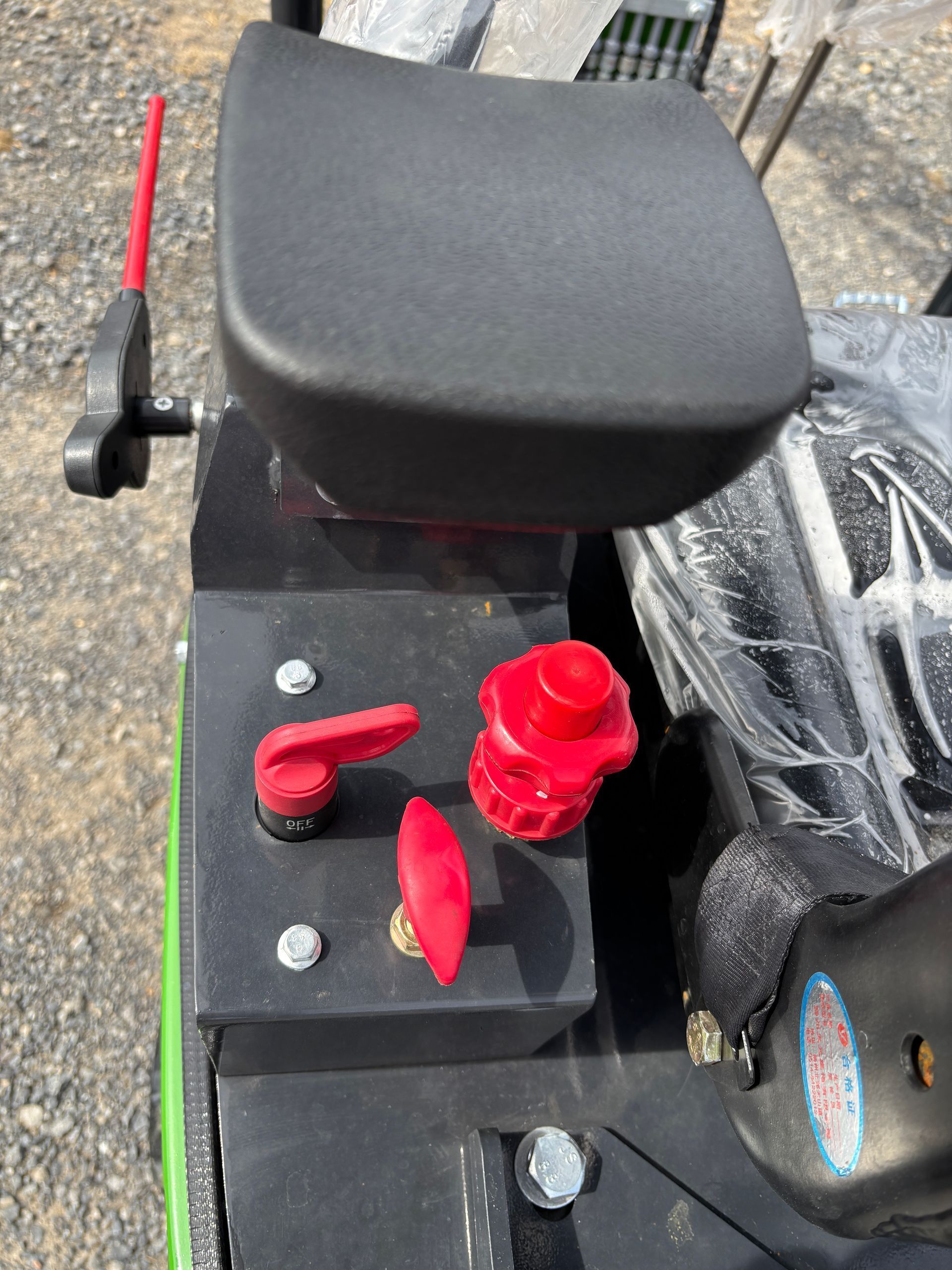 A close-up view of the black control panel on a machine featuring red knobs, levers, and a cushioned seat.