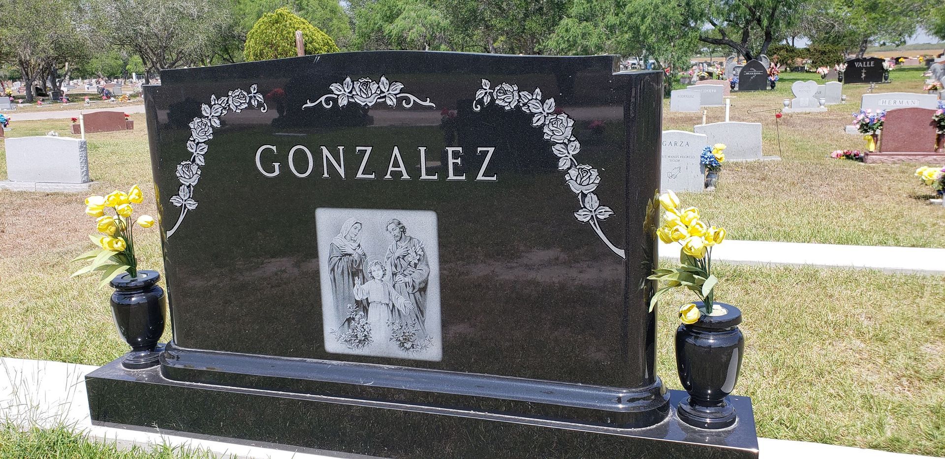 A black gravestone with the name gonzalez on it in a cemetery.
