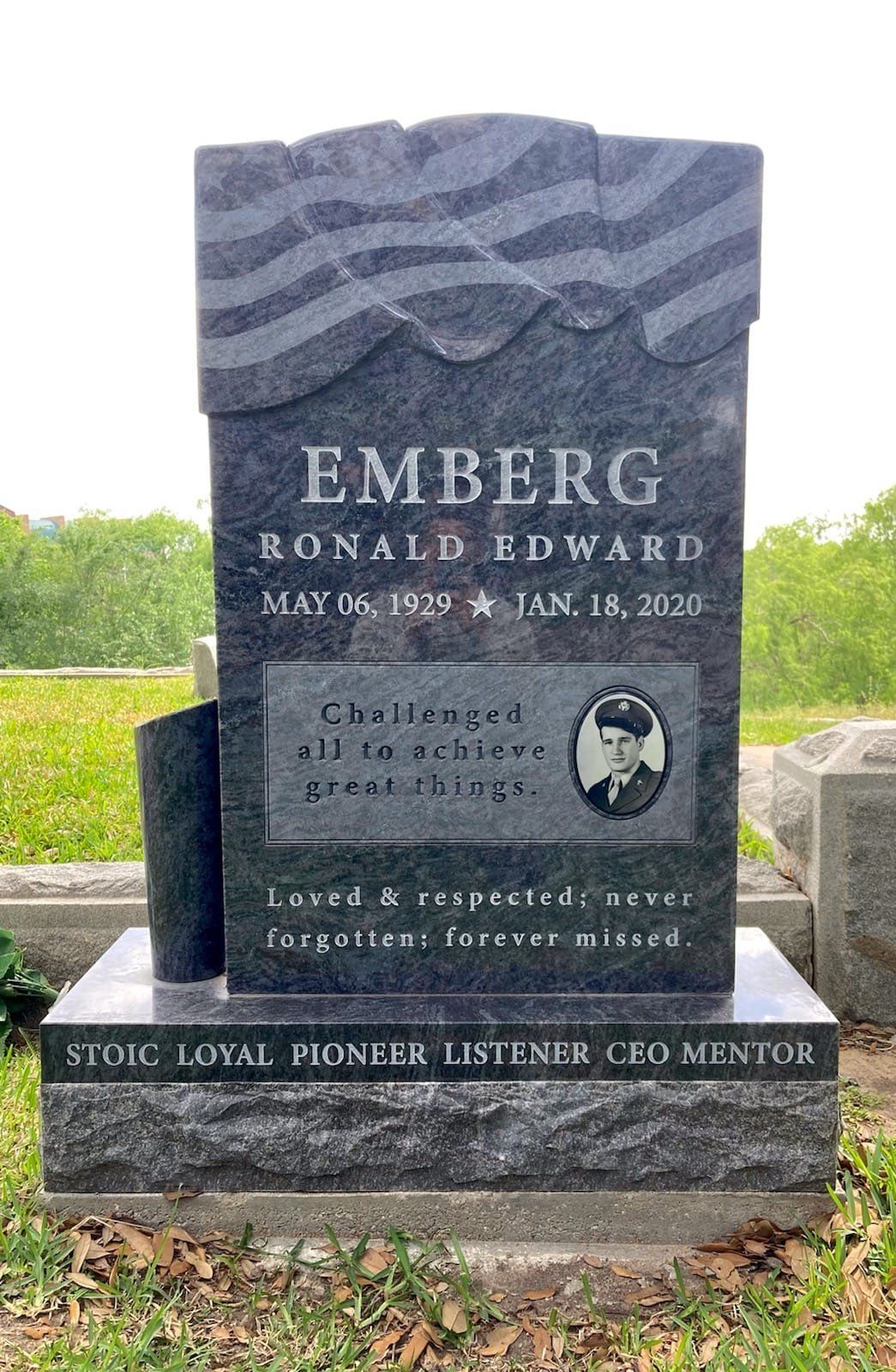 A gravestone for ronald edward emberg is in a cemetery.