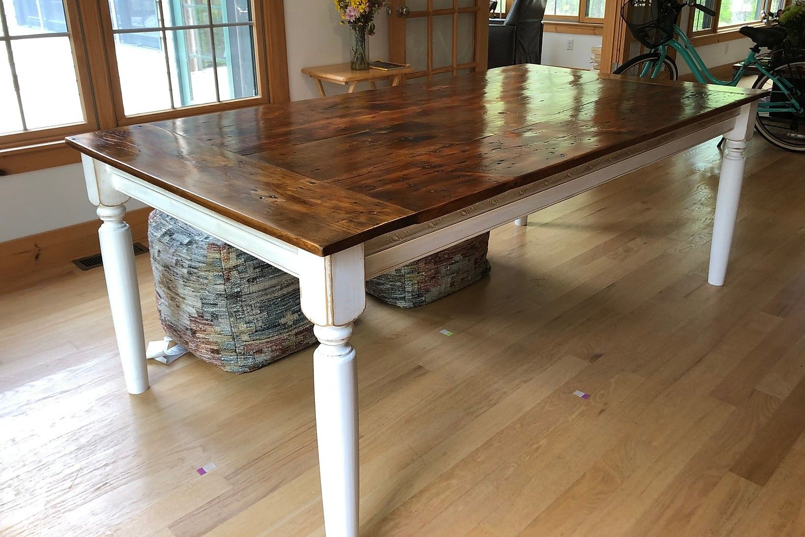 Wooden dining table with white legs and a glossy, brown tabletop.