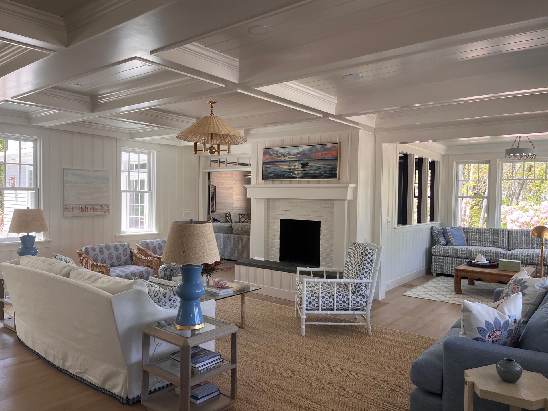 Bright living room with white walls, wood floors, fireplace, and various blue and white patterned furniture.