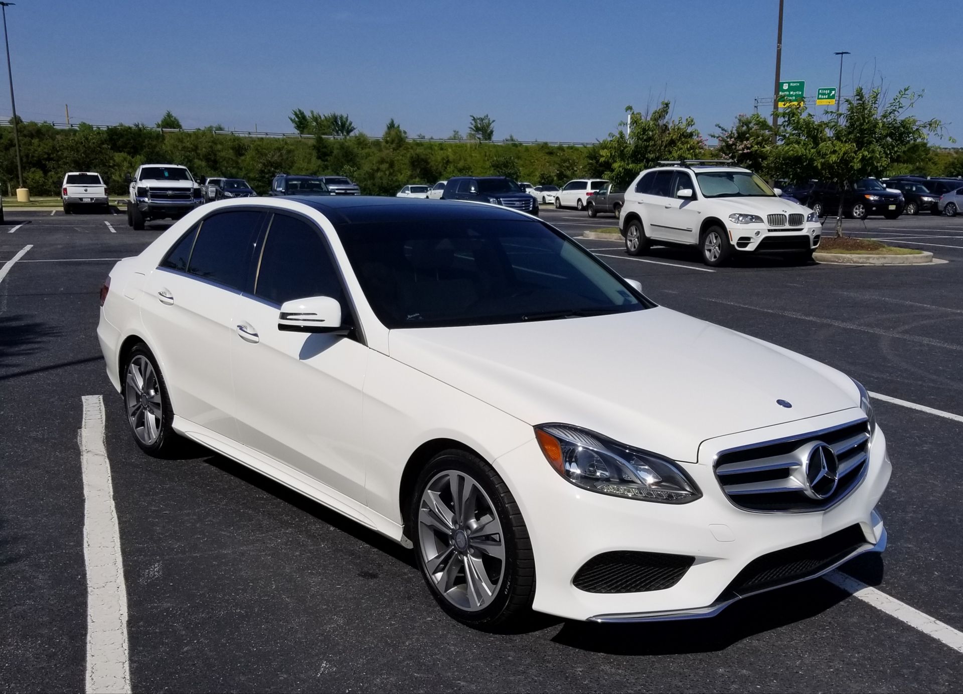 A white mercedes is parked in a parking lot