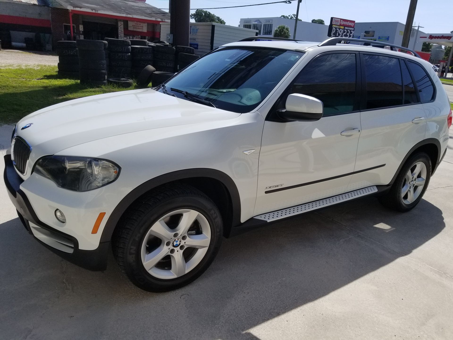 A white bmw x5 is parked in a parking lot.
