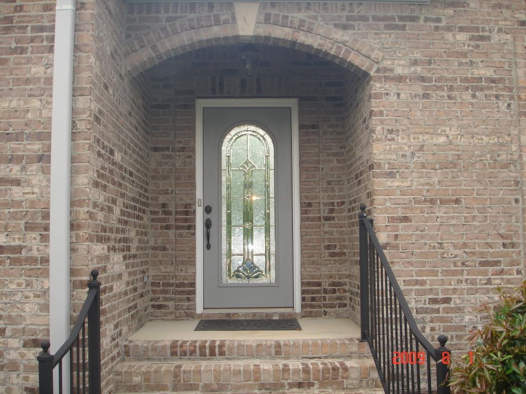 The front door of a brick house has a stained glass window