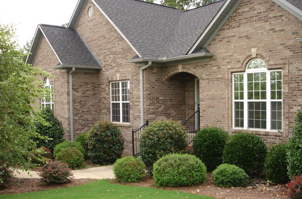 A brick house with a gray roof and white windows