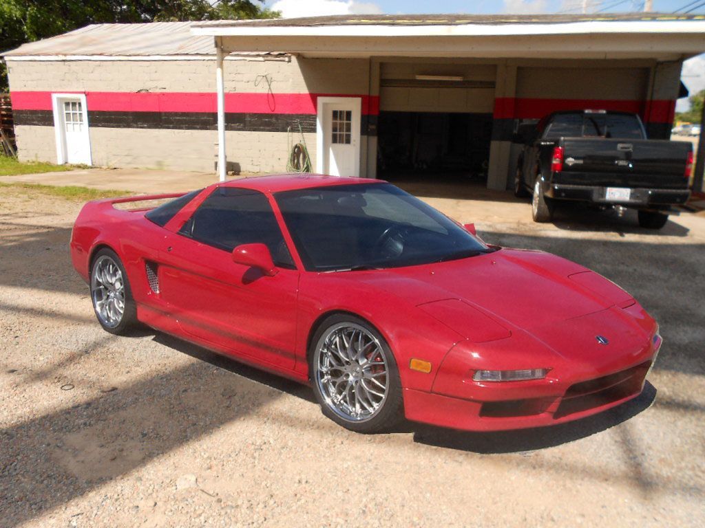 A red sports car is parked in front of a garage.