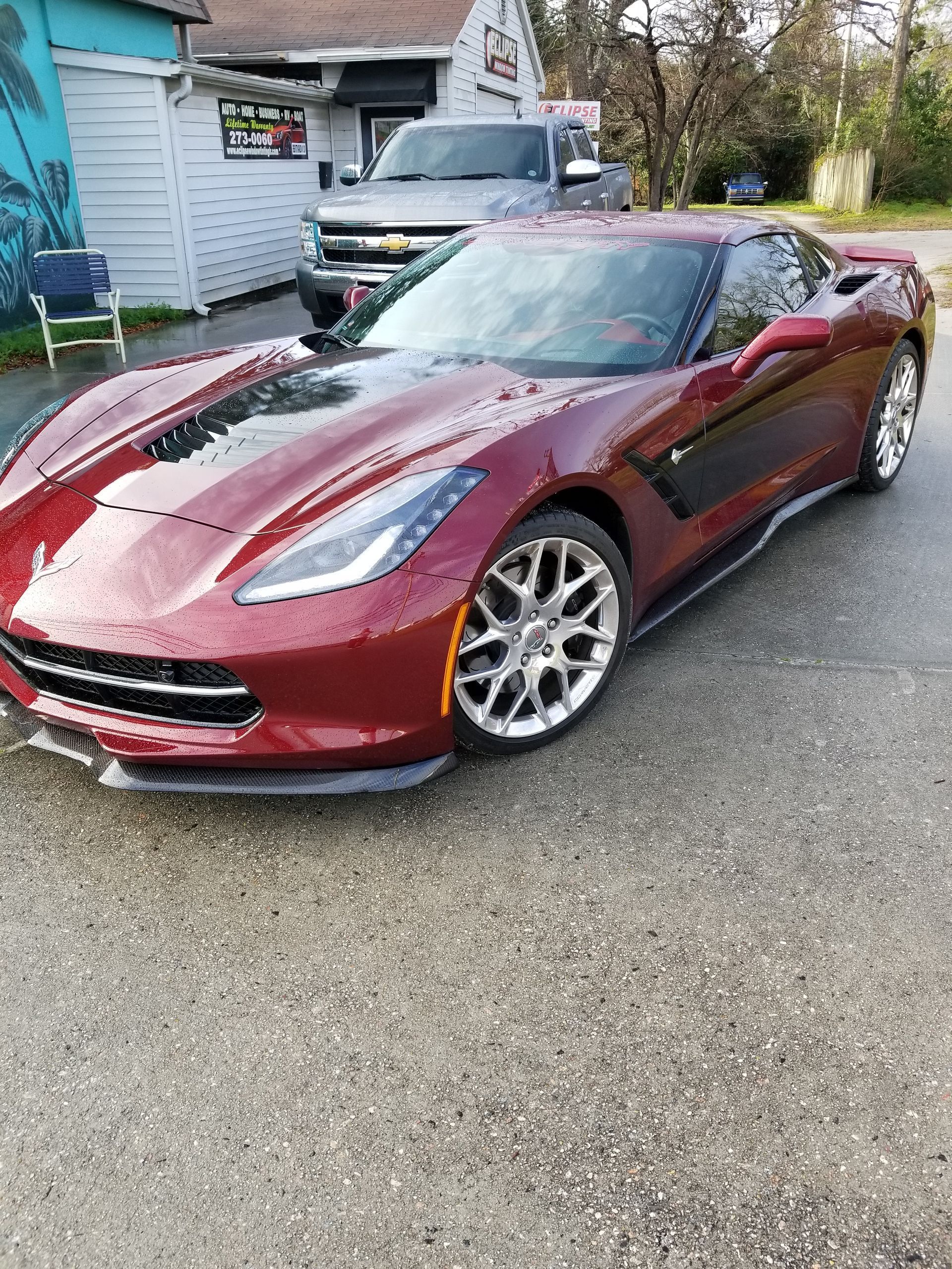 A red corvette is parked in a parking lot in front of a building.