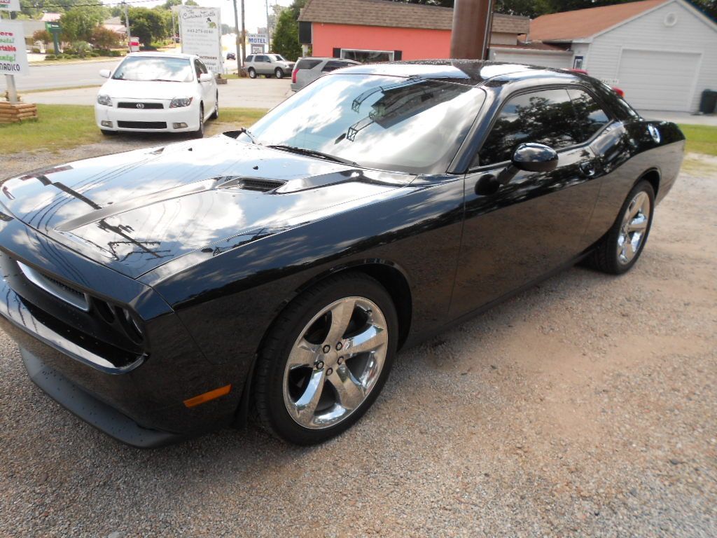 A black dodge challenger is parked on the side of the road