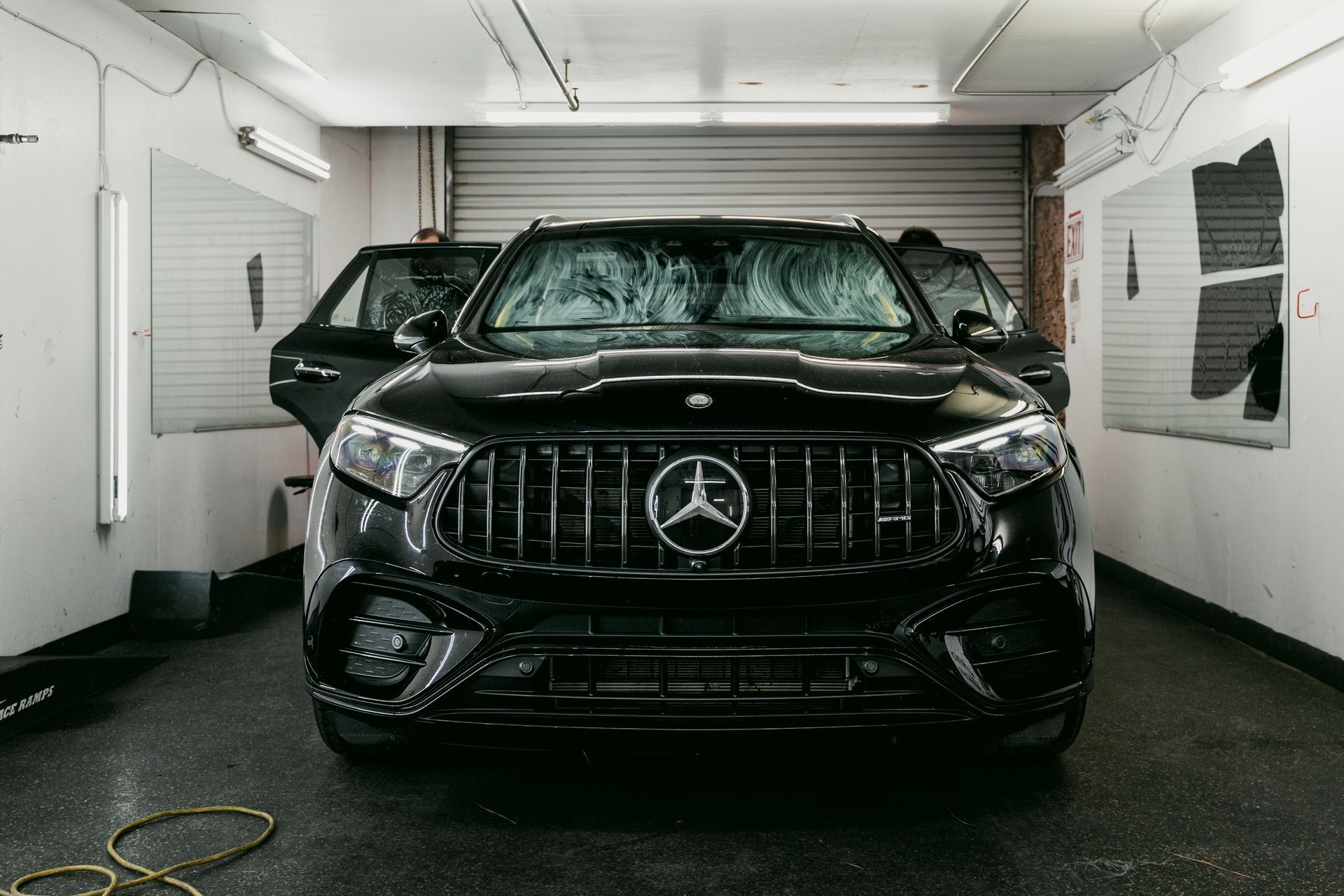 Black Mercedes SUV parked inside a white garage or detailing bay.