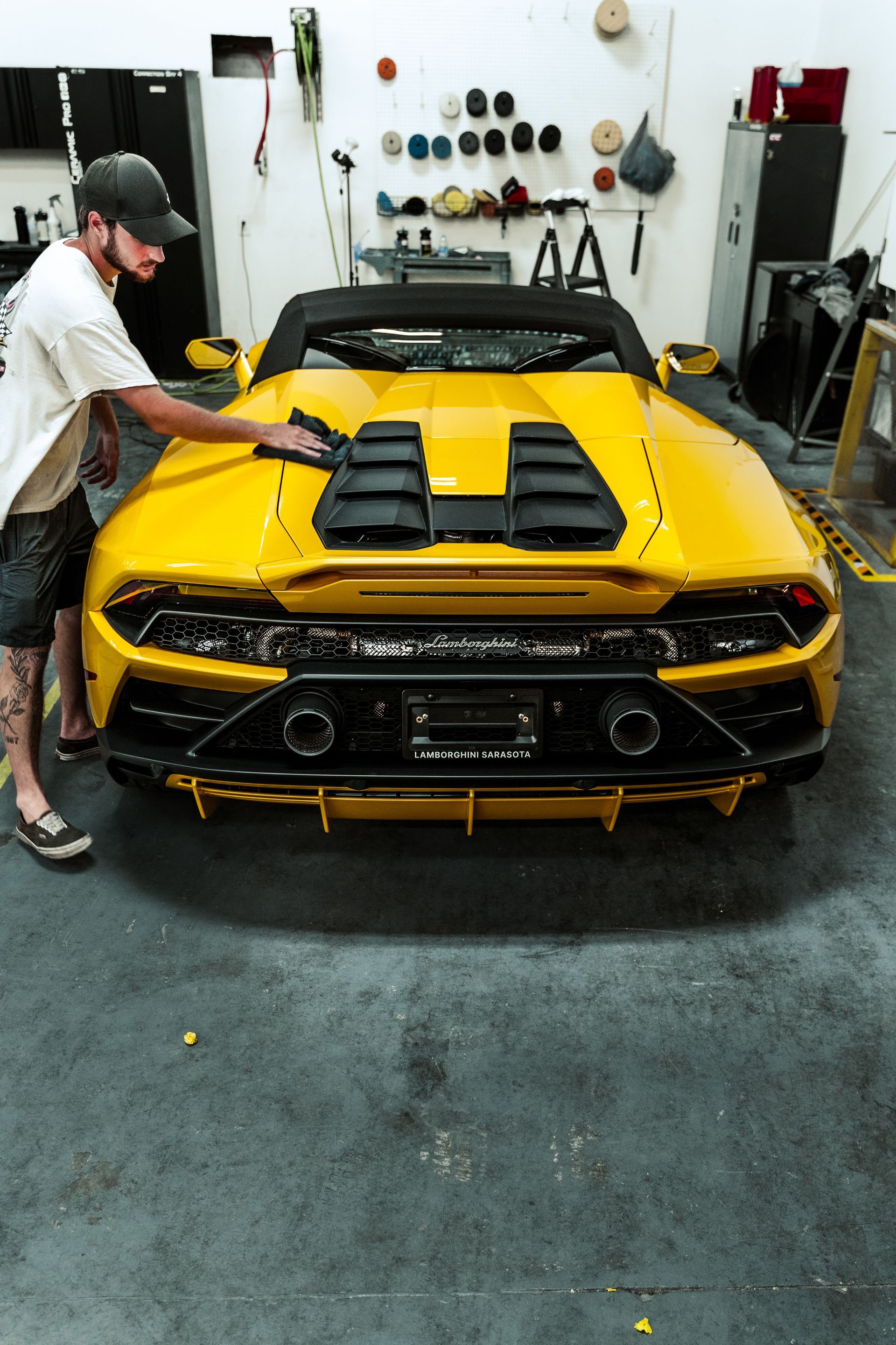 Yellow sports car in a garage with a man working beside it