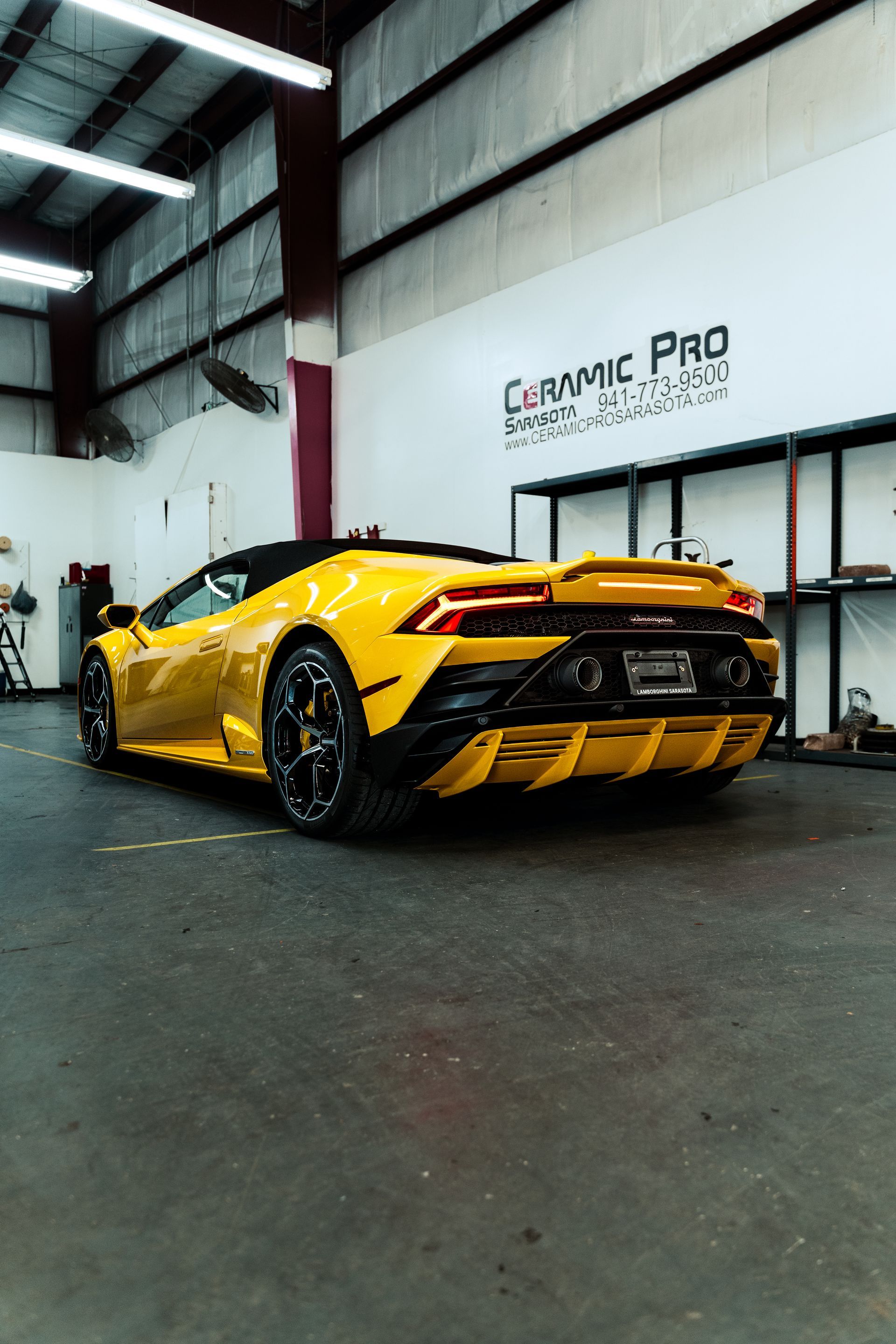 Yellow sports car in a garage with Ceramic Pro signage on the wall